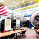 ISS mockup with example racks that fit into the curves of each module sitting behind the chairs.